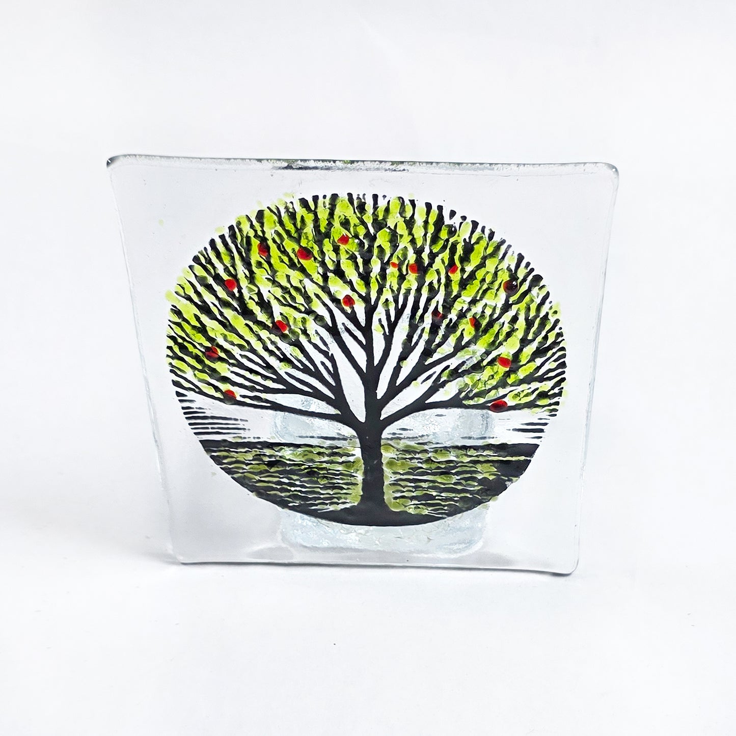 Handmade fused glass tealight holder featuring a green tree design with red accents. A beautiful nature-inspired glass gift for the home.