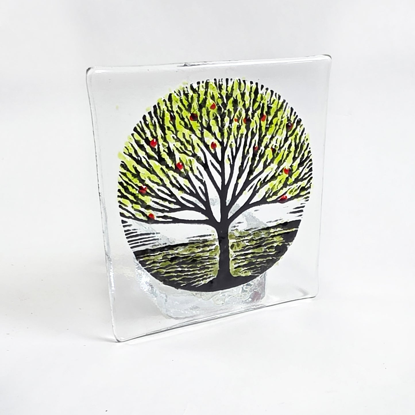 Handmade fused glass tealight holder featuring a green tree design with red accents. A beautiful nature-inspired glass gift for the home.